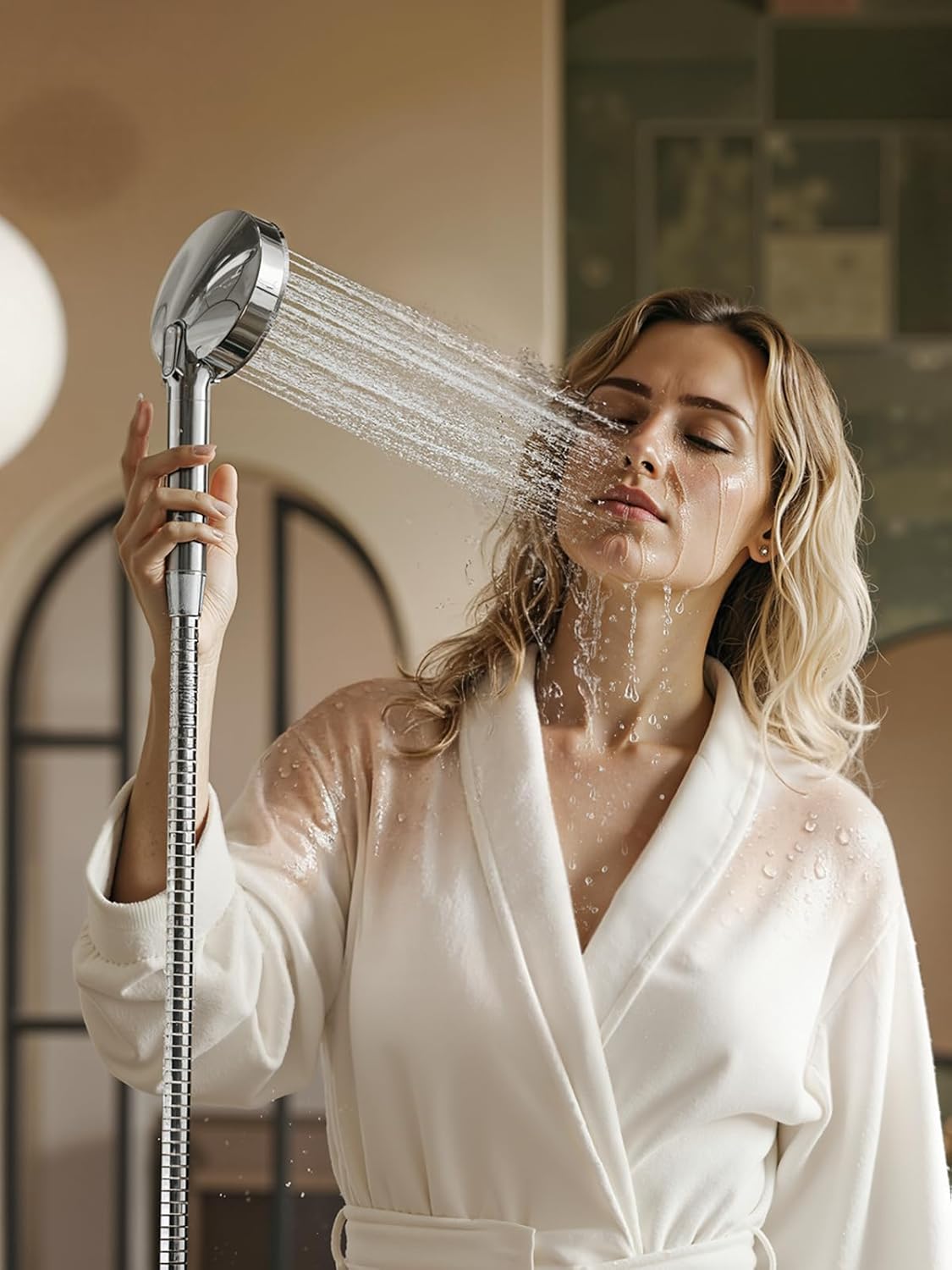 Woman in a white robe rinsing her face with the handheld Cobbe shower head