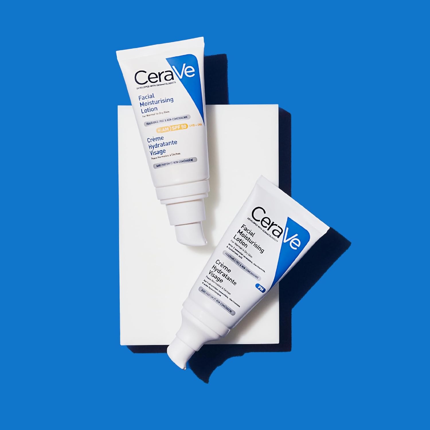 CeraVe AM and PM moisturising lotion tubes in a flat lay on a blue background, showing the morning and evening skincare pairing