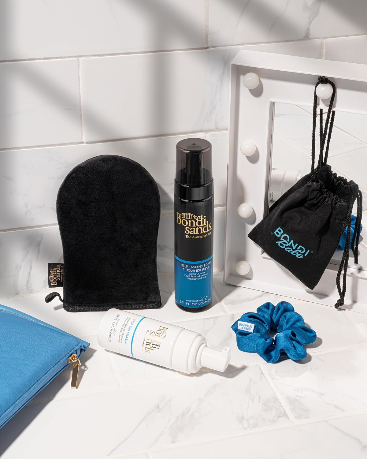 Bondi Sands tanning mitt photographed beside Self Tanning Foam, Self Tan Eraser, a Bondi Babe pouch and a blue scrunchie, none of which are included