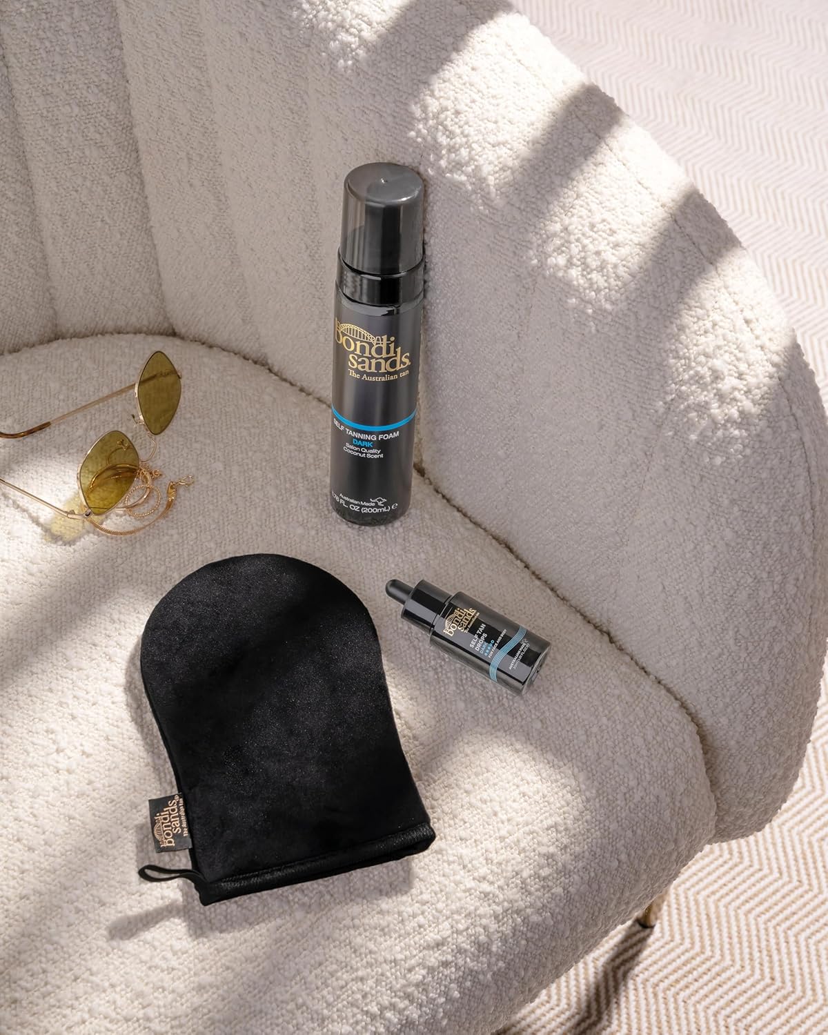 Bondi Sands tanning mitt lying flat beside a 200ml Self Tanning Foam bottle and Self Tan Drops, showing its size