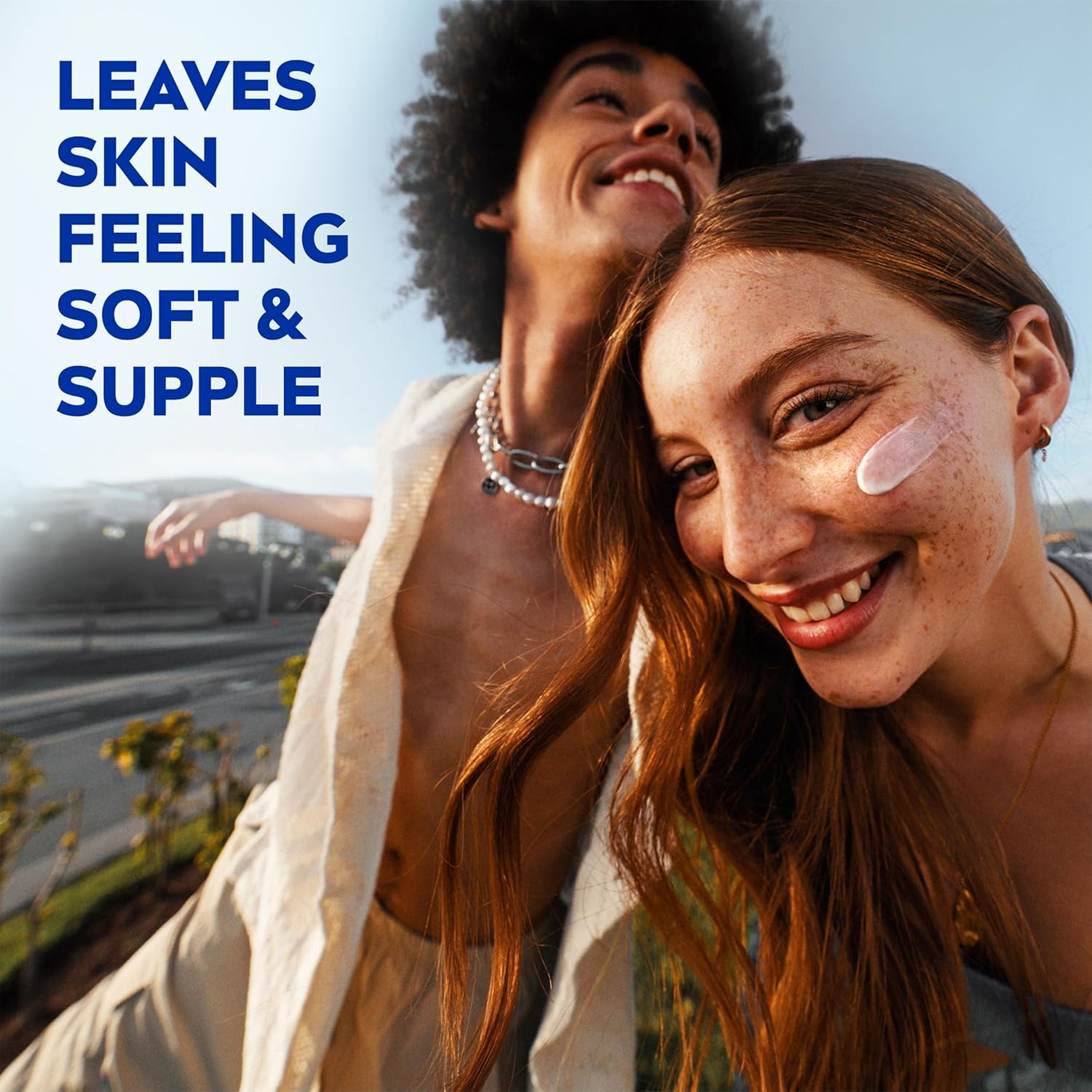 Two smiling people outdoors, one with a swipe of NIVEA Soft cream on her cheek
