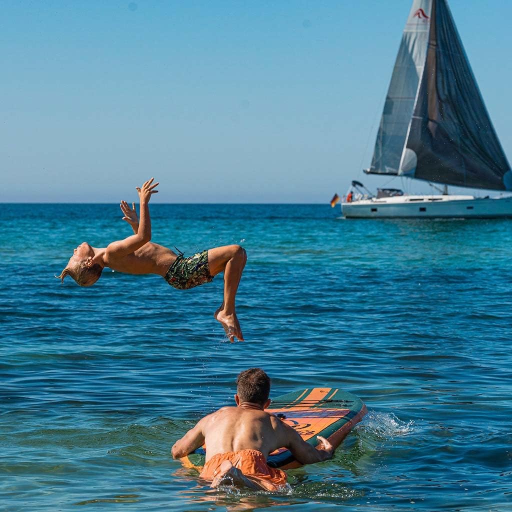 Boy backflipping into the sea next to a man on a paddleboard, the kind of all-day water play P20 Kids is marketed for