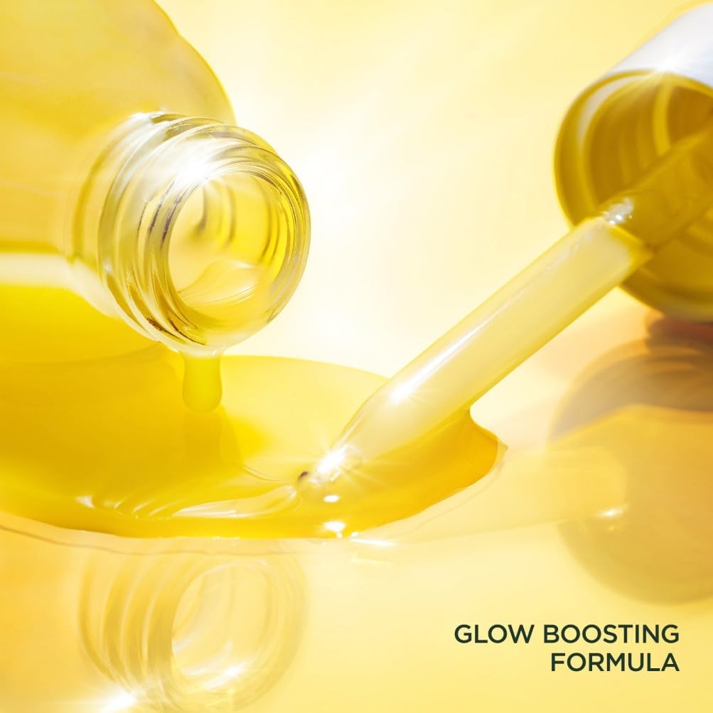 Close-up macro shot of golden serum being dispensed from the dropper, showing the lightweight glow-boosting formula