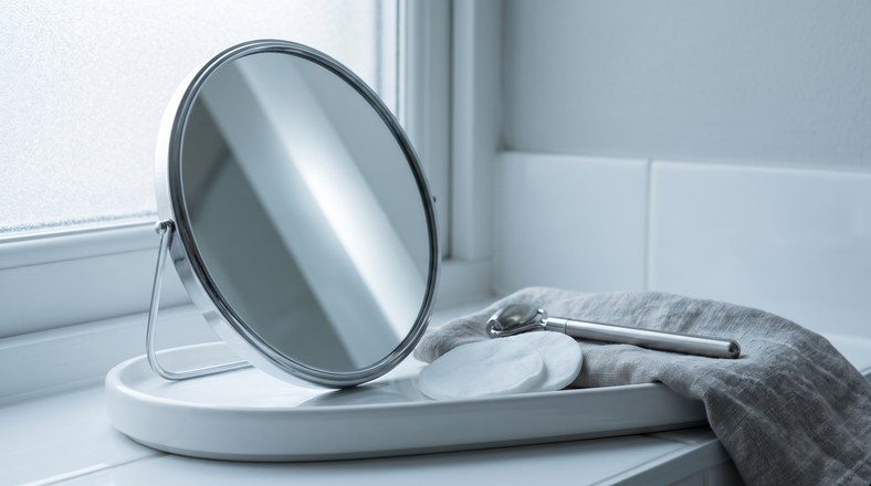 Magnifying mirror and cotton pads used to tell nose blackheads apart from sebaceous filaments