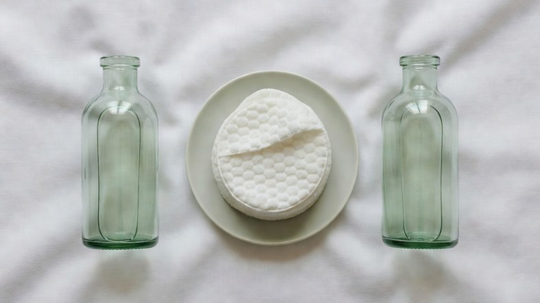Two exfoliant bottles and textured toner pads arranged for combining AHA and BHA in one routine